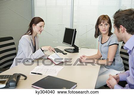 Female real estate agent showing a book to a couple View Large Photo Image Stock Image - Female real estate agent showing a book to a couple. Fotosearch