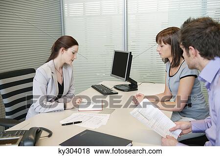 Female real estate agent showing a book to a couple View Large Photo Image Stock Photo - Female real estate agent showing a book to a couple. Fotosearch