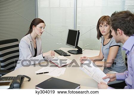 Female real estate agent showing a book to a couple View Large Photo Image Stock Photo - Female real estate agent showing a book to a couple. Fotosearch