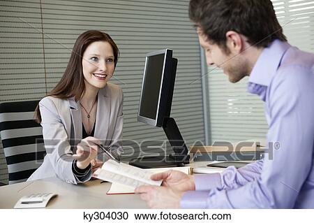 Female real estate agent showing a brochure to a man View Large Photo Image Stock Image - Female real estate agent showing a brochure to a man. Fotosearch