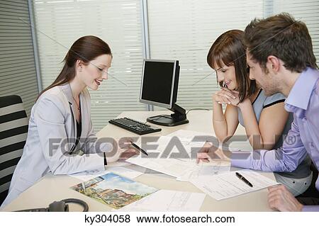 Female real estate agent showing a brochure to a couple View Large Photo Image Stock Photo - Female real estate agent showing a brochure to a couple. Fotosearch