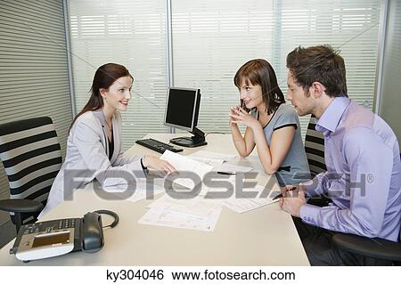 Female real estate agent showing a brochure to a couple View Large Photo Image Stock Photograph - Female real estate agent showing a brochure to a couple. Fotosearch