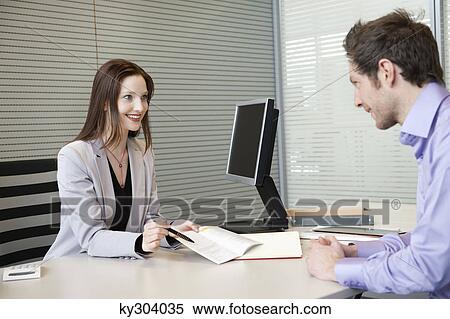 Stock Photography - Female real estate agent showing a brochure to a man. Fotosearch