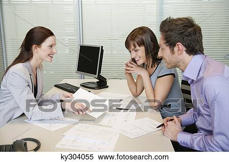 Female real estate agent showing a brochure to a couple View Large Photo Image Stock Photography - Female real estate agent showing a brochure to a couple. Fotosearch