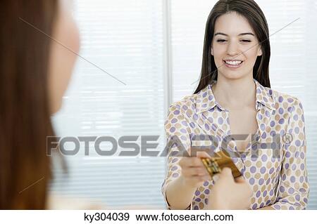 Woman giving a credit card to a businesswoman View Large Photo Image Stock Photo - Woman giving a credit card to a businesswoman. Fotosearch
