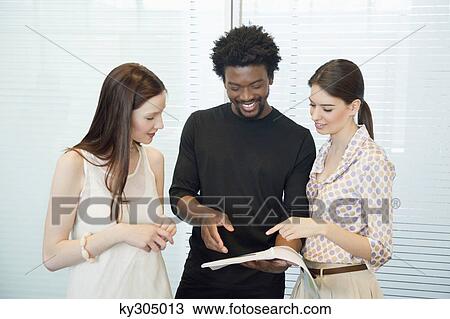 Stock Image - Business executives discussing documents in an office. Fotosearch