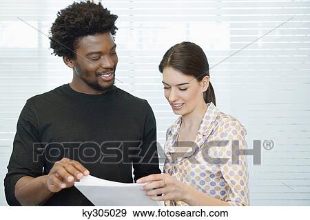 Stock Photo - Business executives discussing documents in an office. Fotosearch