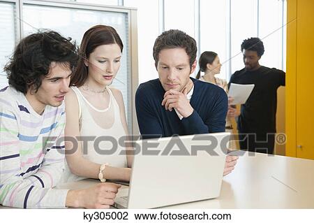 Stock Image - Business executives using a laptop in an office. Fotosearch
