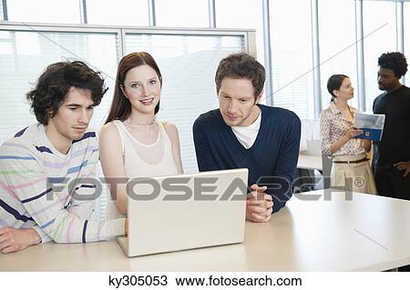 Stock Image - Business executives using a laptop in an office. Fotosearch