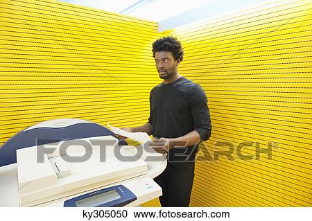 Stock Image - Businessman using a photocopy machine in an office. Fotosearch