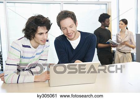 Businessmen using a laptop in an office View Large Photo Image Stock Image - Businessmen using a laptop in an office. Fotosearch