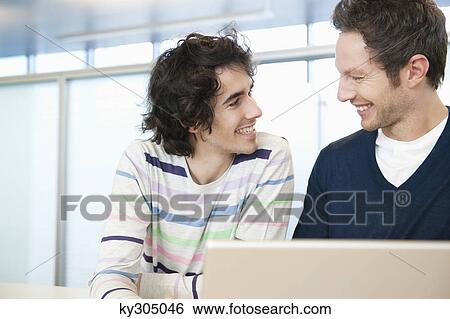 Businessmen using a laptop in an office View Large Photo Image Stock Photograph - Businessmen using a laptop in an office. Fotosearch