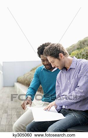 Friends discussing documents on a boardwalk View Large Photo Image Stock Image - Friends discussing documents on a boardwalk. Fotosearch