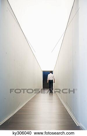 Businessman walking in the corridor of an office View Large Photo Image Stock Image - Businessman walking in the corridor of an office. Fotosearch
