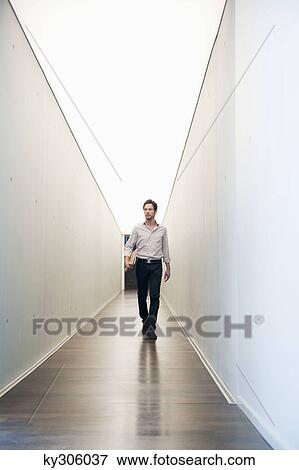 Businessman walking in the corridor of an office View Large Photo Image Stock Photo - Businessman walking in the corridor of an office. Fotosearch