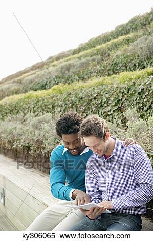 Friends discussing documents on a boardwalk View Large Photo Image Stock Photography - Friends discussing documents on a boardwalk. Fotosearch
