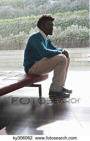 Stock Image - Man sitting on a couch and thinking. Fotosearch