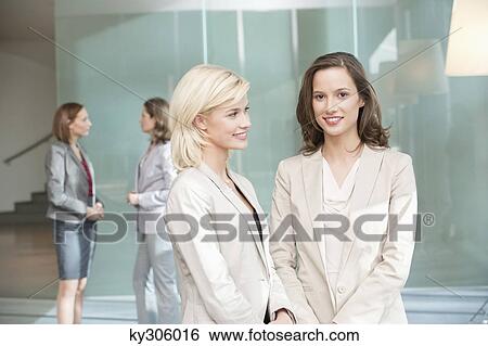 Stock Photograph - Two businesswomen standing together and smiling. Fotosearch