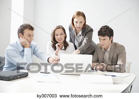 Business executives looking at a laptop in a board room View Large Photo Image Stock Image - Business executives looking at a laptop in a board room. Fotosearch