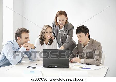 Business executives looking at a laptop in a board room View Large Photo Image Stock Photograph - Business executives looking at a laptop in a board room. Fotosearch