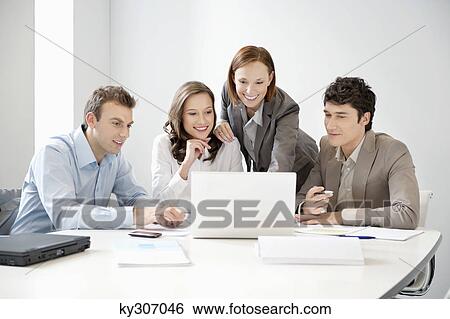 Business executives looking at a laptop in a board room View Large Photo Image Stock Photograph - Business executives looking at a laptop in a board room. Fotosearch