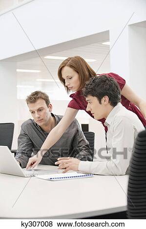Businesswoman with two businessmen working in an office View Large Photo Image Stock Photo - Businesswoman with two businessmen working in an office. Fotosearch
