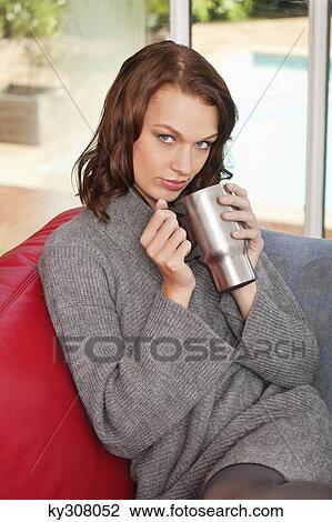 Stock Image - Young woman holding cup. Fotosearch