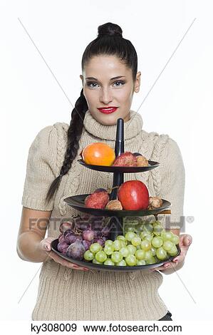 Young woman holding fruit dish View Large Photo Image Stock Photo - Young woman holding fruit dish. Fotosearch