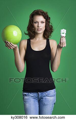 Young woman holding green ball and light bulb View Large Photo Image Stock Photograph - Young woman holding green ball and light bulb. Fotosearch