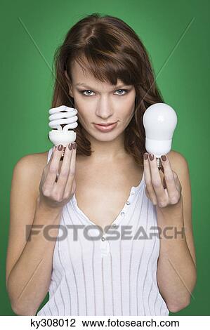 Stock Image - Young woman holding two light bulbs. Fotosearch