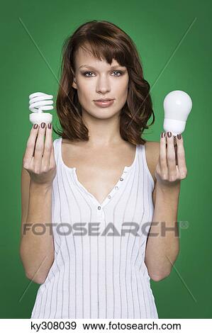 Young woman holding two light bulbs View Large Photo Image Stock Photo - Young woman holding two light bulbs. Fotosearch