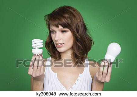 Young woman holding two light bulbs View Large Photo Image Stock Photo - Young woman holding two light bulbs. Fotosearch