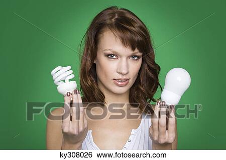 Young woman holding two light bulbs View Large Photo Image Stock Photograph - Young woman holding two light bulbs. Fotosearch