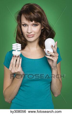 Young woman holding two light bulbs View Large Photo Image Stock Photograph - Young woman holding two light bulbs. Fotosearch