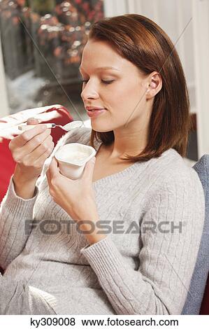 Young woman eating a yogurt View Large Photo Image Stock Photo - Young woman eating a yogurt. Fotosearch