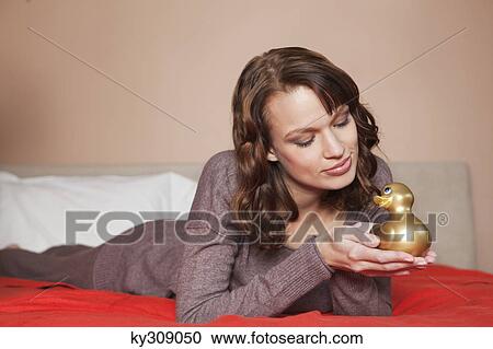 Young woman holding a rubber duck in bed View Large Photo Image Stock Image - Young woman holding a rubber duck in bed. Fotosearch