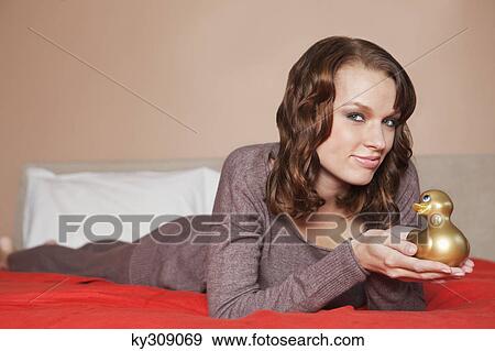 Young woman holding a rubber duck in bed View Large Photo Image Stock Photo - Young woman holding a rubber duck in bed. Fotosearch
