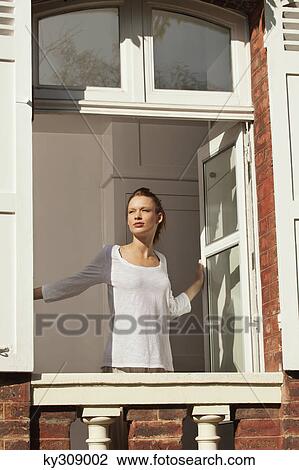 Stock Image - Young woman opening window. Fotosearch