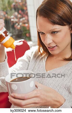 Young woman pouring honey into her tea cup View Large Photo Image Picture - Young woman pouring honey into her tea cup. Fotosearch