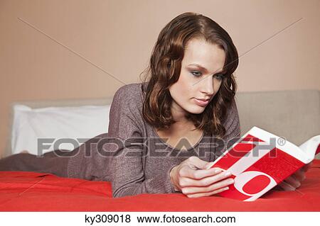 Stock Photo - Young woman reading a book in bed. Fotosearch