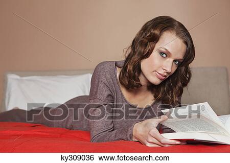Young woman reading a book in bed View Large Photo Image Stock Photograph - Young woman reading a book in bed. Fotosearch