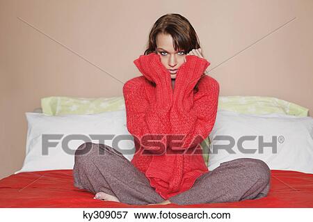 Stock Photo - Young woman sitting cross-legged in bed. Fotosearch