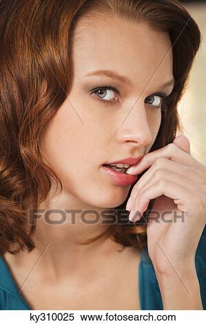 Stock Photography - Young woman with finger in mouth. Fotosearch