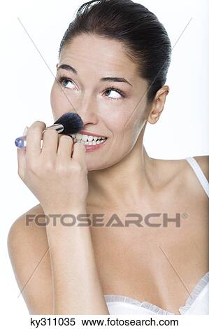 Stock Photography - Young woman applying blush. Fotosearch