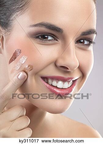 Young woman applying foundation View Large Photo Image Stock Photo - Young woman applying foundation. Fotosearch