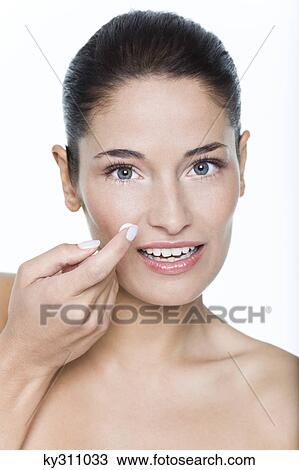 Stock Image - Young woman applying moisturizer. Fotosearch