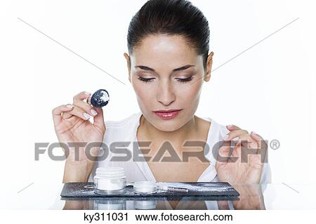 Stock Image - Young woman holding make-up brush. Fotosearch