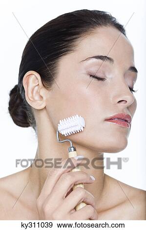 Young woman using facial massage roller View Large Photo Image Stock Photo - Young woman using facial massage roller. Fotosearch