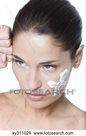 Stock Photograph - Young woman with moisturizer on her cheek. Fotosearch