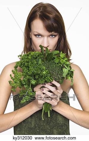 Stock Image - Young woman holding fresh herbs. Fotosearch
